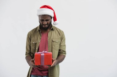 Noel Baba şapkası mevcut kutusu beyaz izole bakarak üzgün Afrikalı-Amerikalı adam
