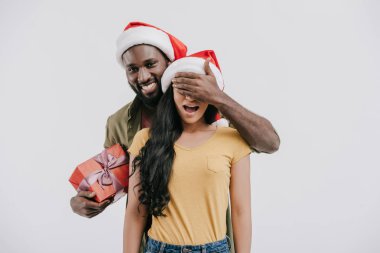 kız gözlerini kapatma ve yeni yıl hediyesi beyaz izole tutan Afro-Amerikan erkek