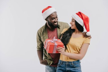 Afro-Amerikan kaç Noel Baba şapkaları birbirine bakarak ve mevcut holding beyaz izole içinde gülümseyen
