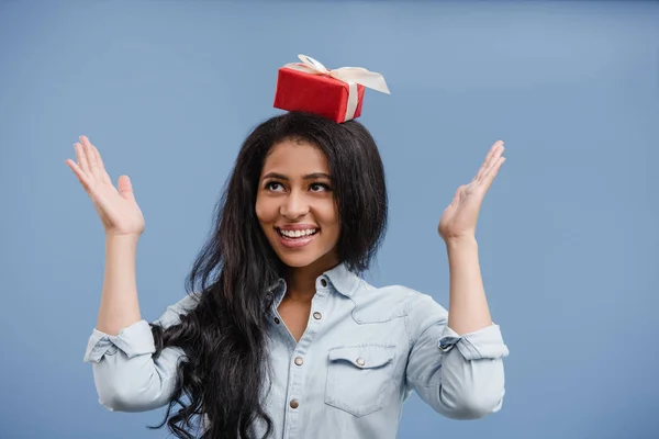 青に分離の頭の上の赤いギフト箱を持って幸せな魅力的なアフリカ系アメリカ人女の子 — ストック写真