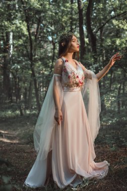 mystic elf in character in flower dress walking in woods clipart