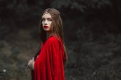 gyönyörű lány piros köpenyt és elegáns koszorú erdőben