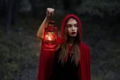 elegáns misztikus lány séta a sötét erdőben, a petróleumlámpa