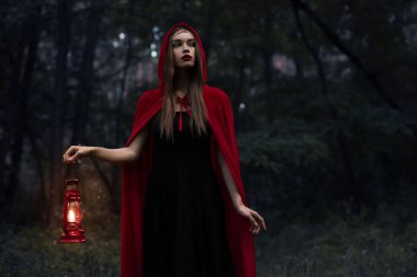 karanlık ormanda yürüyüş gaz lambası ile kırmızı pelerin zarif mistik kız 