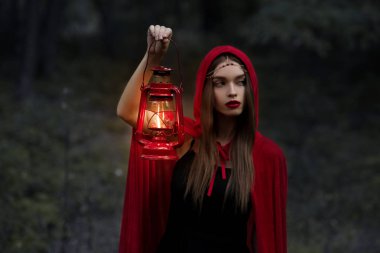 elegant mystic girl walking in dark forest with kerosene lamp clipart