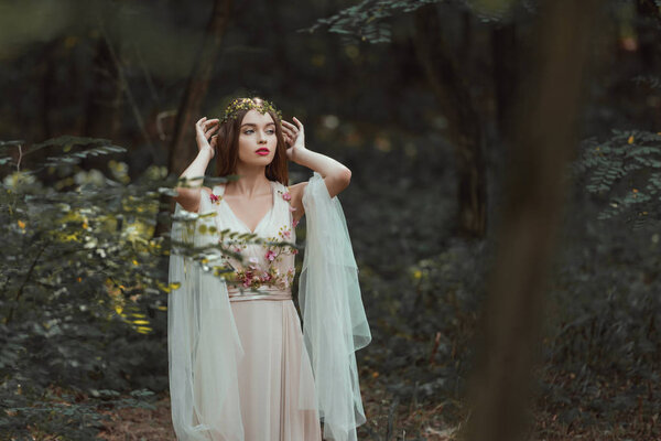 fantasy girl with elf ears in flower dress posing in forest