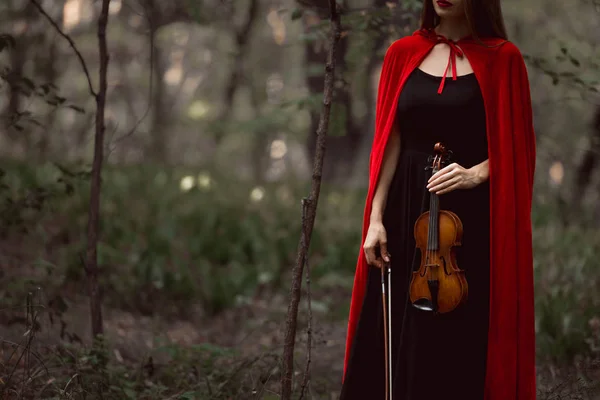 Обрізаний Вид Елегантної Жінки Червоному Плащі Тримає Скрипку Темних Лісах — стокове фото