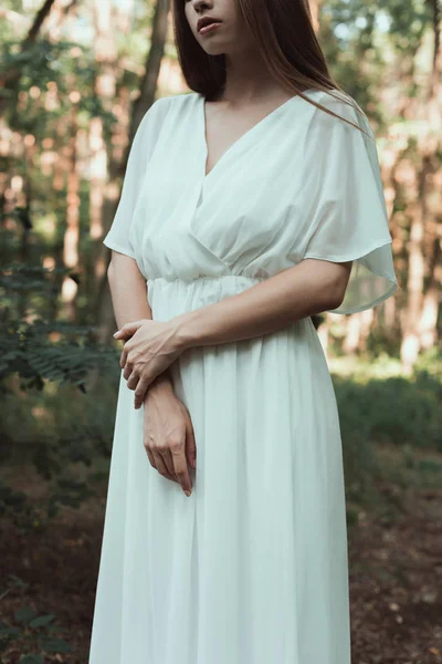 中央部を森でポーズをとって白いドレスでエレガントな優しい女の子の表示します — ストック写真