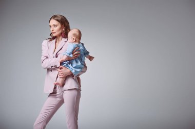 sevimli bebek kızı taşıyan ve dış saha üzerinde izole gri arıyorum güzel şık genç anne