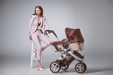 Bebek taburede oturan ve uzak gri görünümlü arabası olan moda kadın
