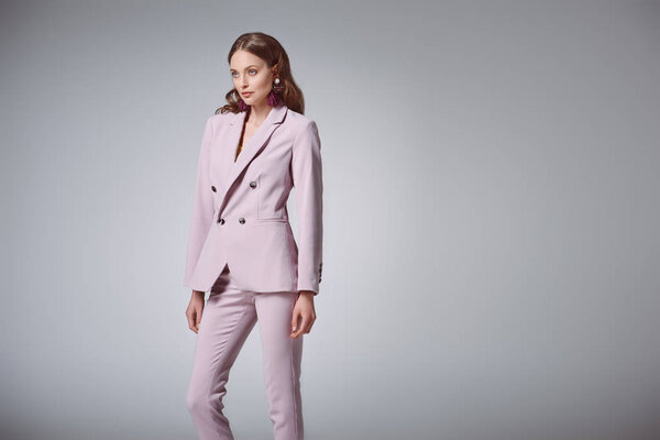 attractive woman in fashionable pink suit looking away isolated on grey