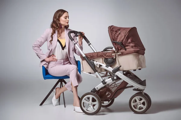 Bela Elegante Jovem Mulher Sentada Cadeira Olhando Para Carruagem Bebê — Fotografia de Stock