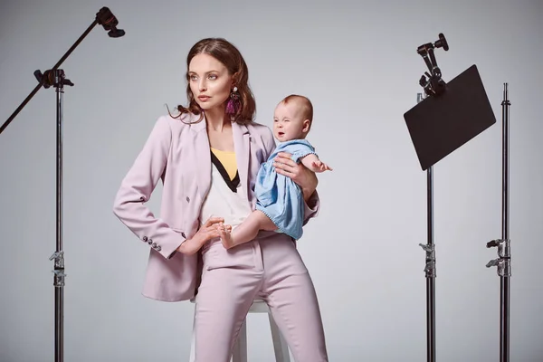 Moda Jovem Mãe Segurando Adorável Bebê Filha Enquanto Sentado Cadeira — Fotografia de Stock