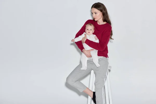 Stylish Young Mother Holding Infant Daughter Sitting Stool Grey — Free Stock Photo