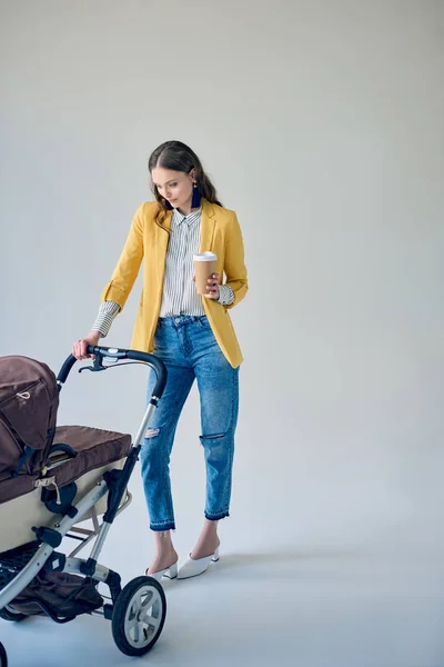 Fashionable Young Woman Holding Disposable Coffee Cup Looking Baby Stroller — Stock Photo, Image