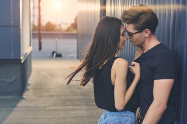beautiful hot interracial couple hugging and going to kiss on roof with sunlight clipart