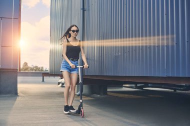 çekici Asyalı kız sürme scooter güneş ışığı ile çatı üzerinde