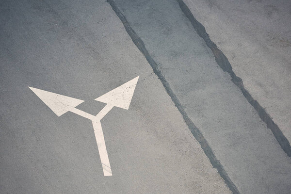 символ стрелки в двух направлениях на серой асфальтовой дороге
