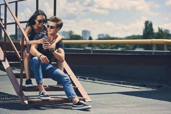 Glückliches Multikulturelles Paar Mit Einer Flasche Whiskey Auf Einer Treppe — kostenloses Stockfoto