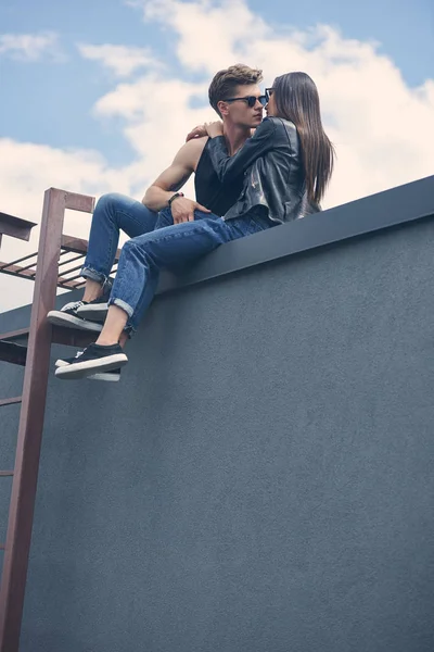 屋根の上に座っている間にキスをするスタイリッシュなセクシーな民族カップル行くの底面図 — ストック写真