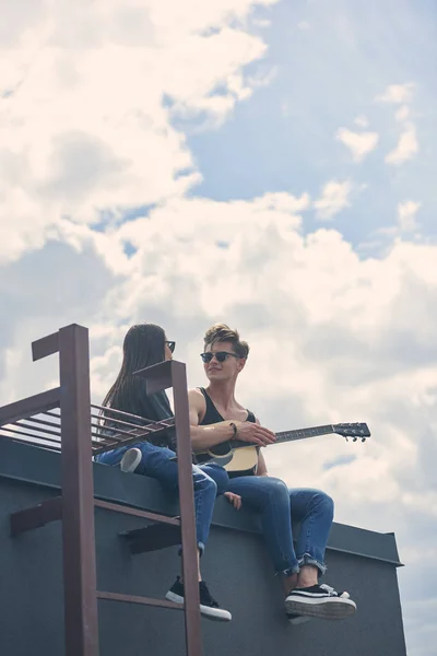 男子为他的亚洲女友在屋顶上演奏的声波吉他 — 免费的图库照片