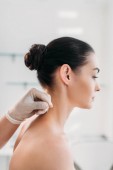 Schnappschuss von Kosmetikerin, die bei Akupunkturtherapie im Wellness-Salon Nadeln auf Frauenkörper legt
