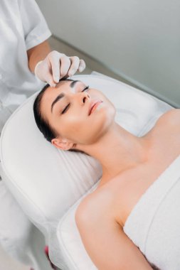 kısmi görünümünü iğneler spa salonda akupunktur tedavisi sırasında kadının alnına koyarak güzellik uzmanı