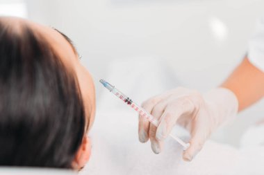 Güzellik uzmanı kadeh spa salonda güzel kadına güzellik enjeksiyon yapma şırınga ile lateks eldiven kırpılmış