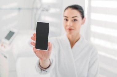 beyaz bornoz smartphone boş ekran ile spa salonda gösterilen kadında 