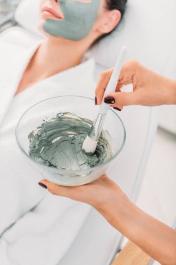 Güzellik uzmanı kase kil maskesi ve spa salonda fırça ile seçici odak