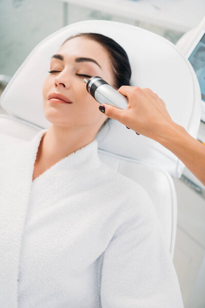 attractive woman getting facial microcurrent therapy in spa salon