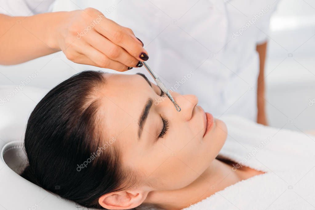 Beautiful woman receiving facial cleansing in spa center