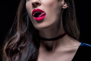 cropped view of sexy vampire woman licking her lips isolated on black clipart