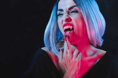 vampir kadın siyah izole kan ile orta parmağını yalama