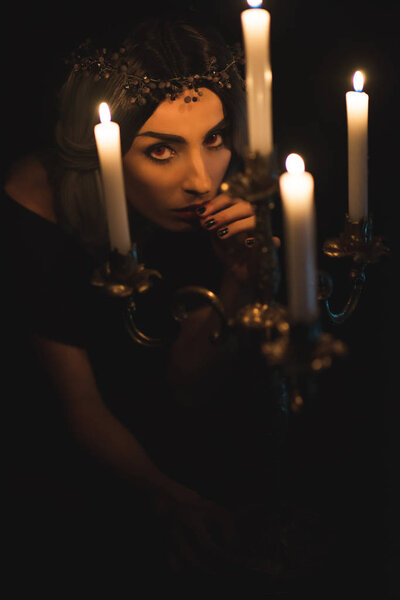 привлекательная женщина с винтажным канделябром на темном фоне
