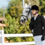 Handsome male equestrian standing near horse at horse club