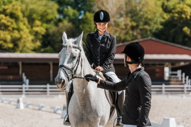 Erkek equestrians at yular, kadın jokey at at kulübünde oturup holding