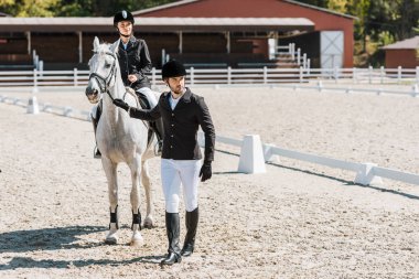 yakışıklı equestrians at yular, kadın jokey at çiftliği nde oturan holding