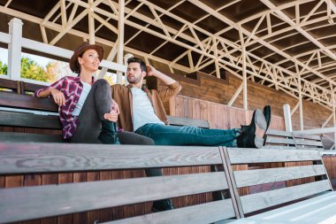 colleagues in casual clothes sitting on bench at ranch stadium clipart