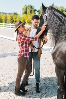 kadın ve erkek jockeys Ranch'te siyah at palming