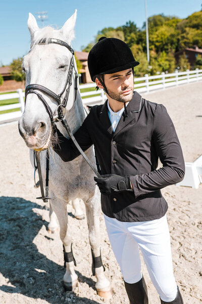Красивый конный мужчина держит уздечку в конном клубе
