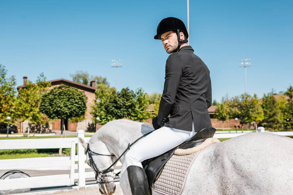 handsome male equestrian in professional apparel sitting on horseback at horse club