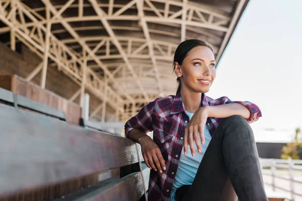 Attraente Donna Camicia Scacchi Seduto Sulla Panchina Allo Stadio Ranch — Foto stock gratuita