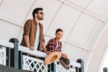 man and woman leaning on tribune railing and holding hats at ranch stadium clipart