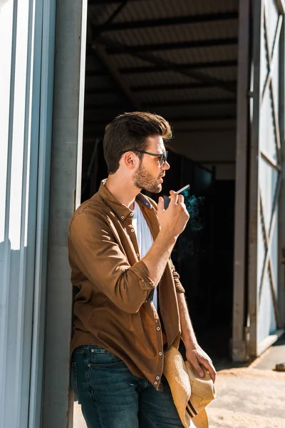 Side View Handsome Man Sunglasses Smoking Cigarette Leaning Wall Ranch — Free Stock Photo