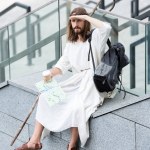 Jesus in robe and crown of thorns sitting on staircase side, holding disposable coffee cup and map, looking away