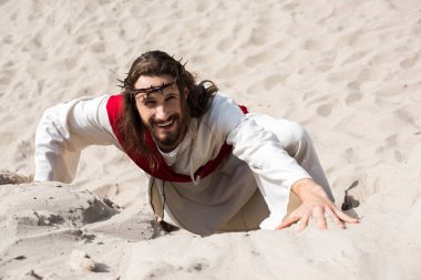çöl ve kameraya bakarak kumlu tepe tırmanma gülümseyen İsa'nın yüksek açılı görünüş
