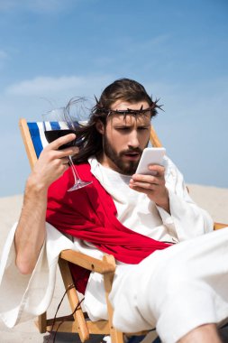 güneşlenme kadeh şarap ile dinlenme ve smartphone çölde bakarak sürpriz İsa