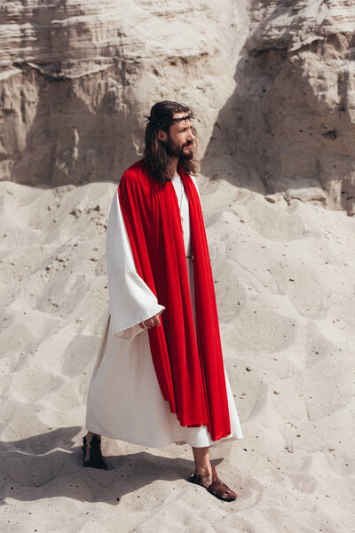 side view of Jesus in robe, red sash and crown of thorns walking in desert