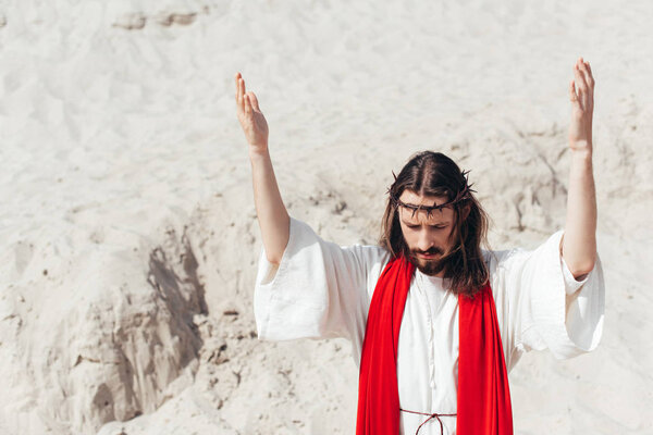 Jesus standing with raised hands and praying in desert